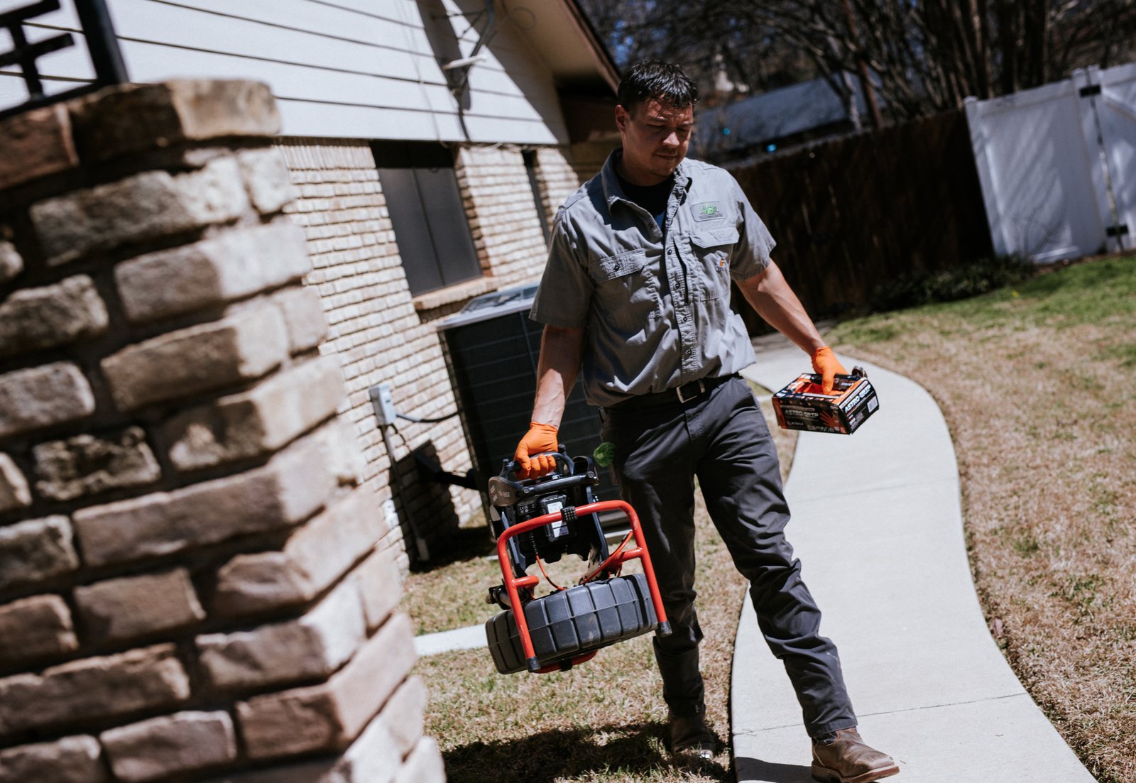Tioga Plumbing plumber carrying a drain camera up the walk to a DFW customer's home