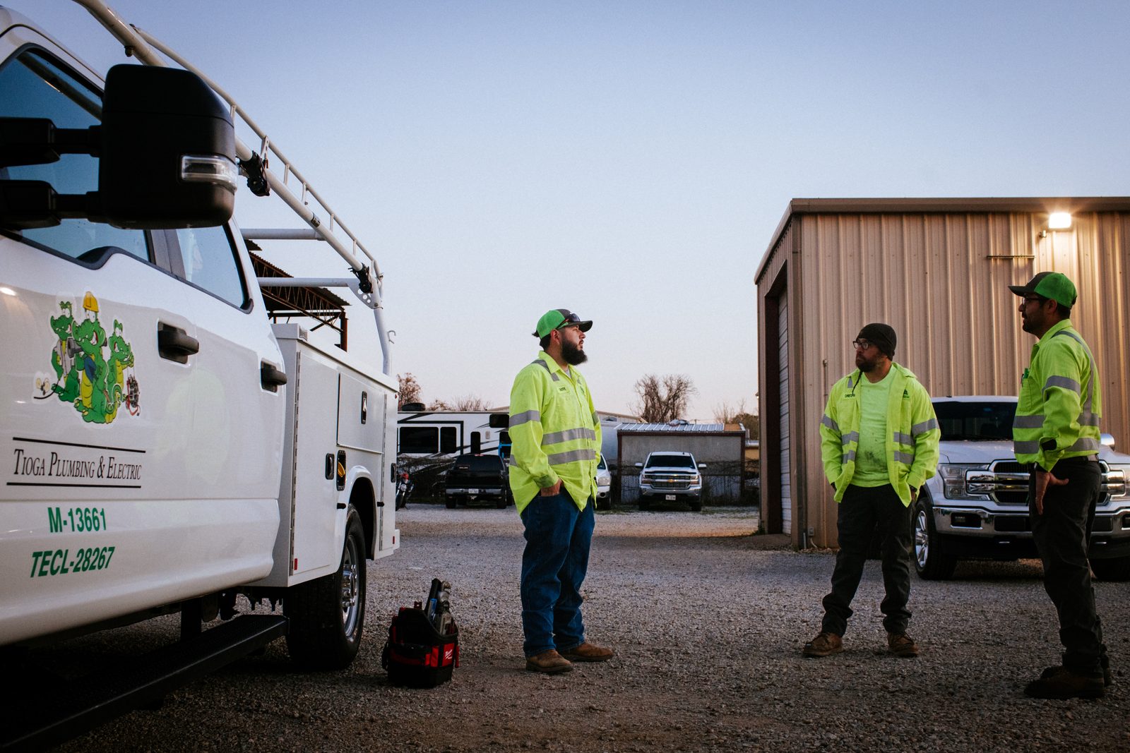 Tioga Plumbing crew in safety yellow beside a branded truck at the Hurst shop