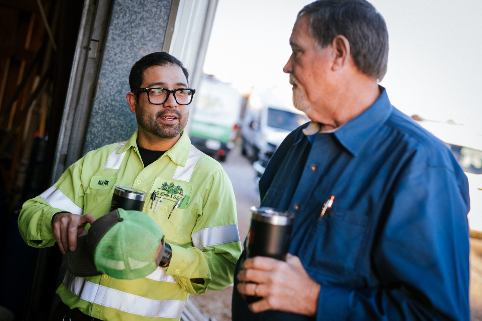 Two Tioga Plumbing team members talking coffee in hand at the Hurst shop