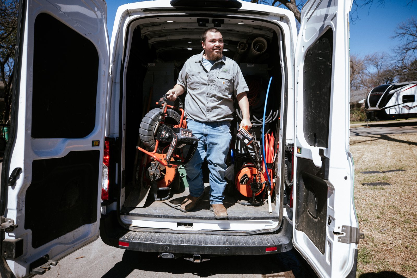 Tioga Plumbing plumber unloading a drain camera from the back of the service van