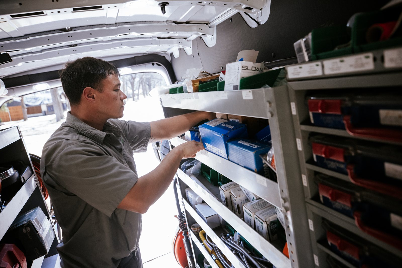 Tioga Plumbing plumber pulling parts from the shelves inside the service van