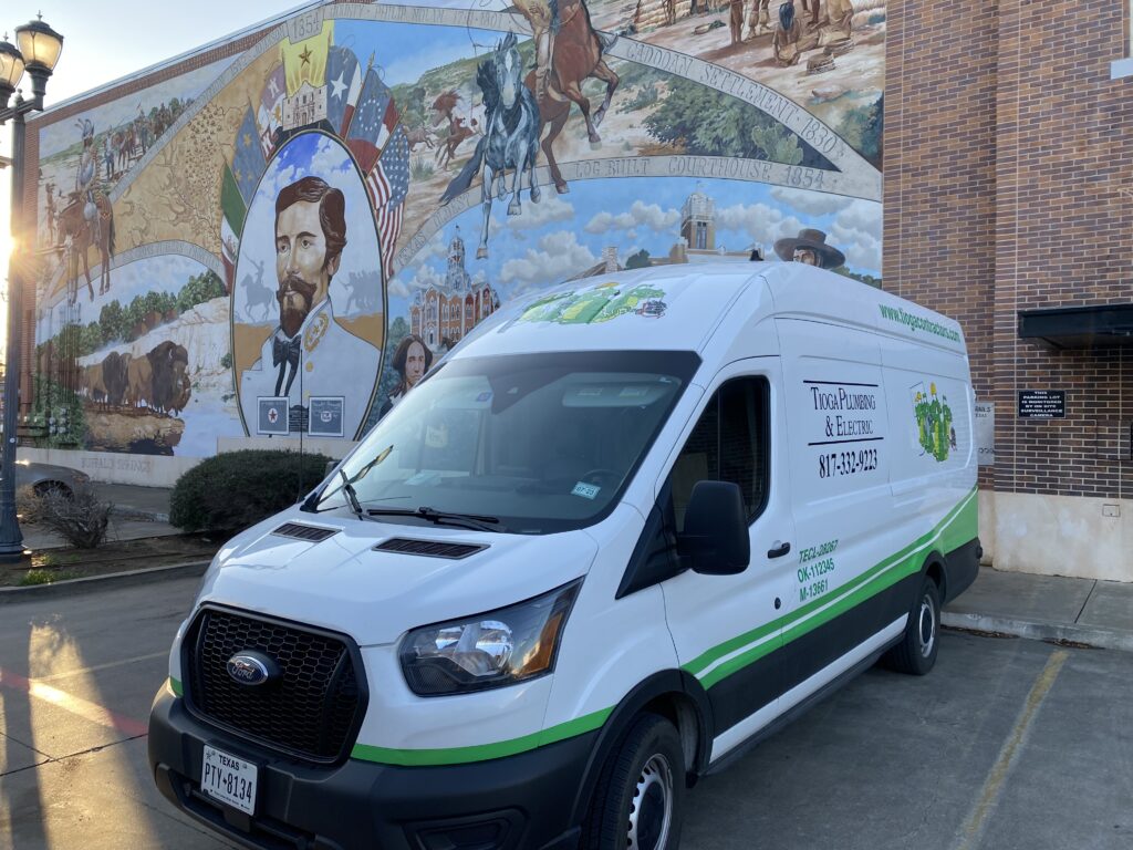 A Tioga Plumbing & Electric service van in front of the Murals of Cleburne in Wright Plaza in Cleburne Texas