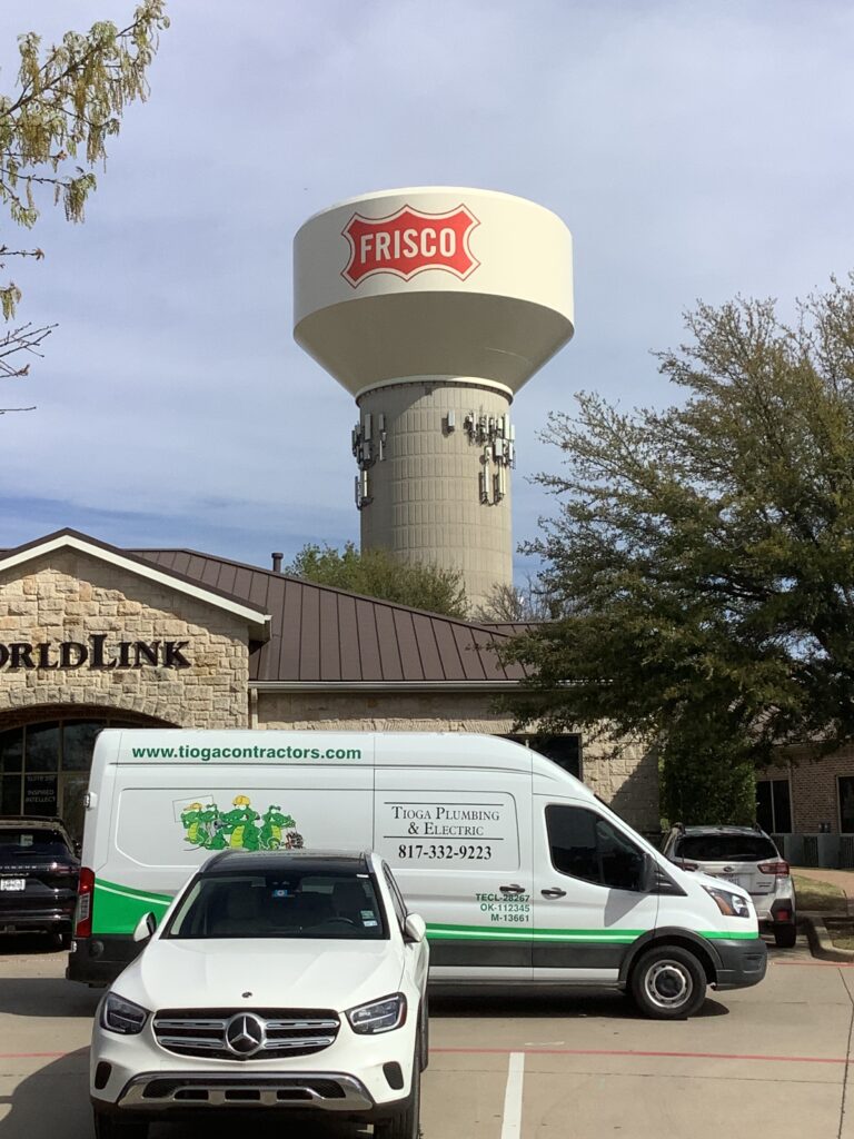 One of the Tioga Plumbing & Electric vans in front of WorldLink and a water tower in Frisco Texas