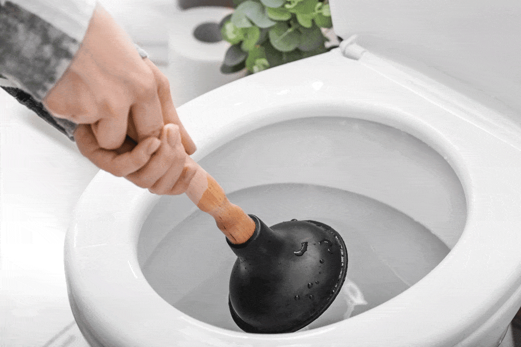 man holding toliet plunger over toilet | plumbing company bedford tx arlington tx