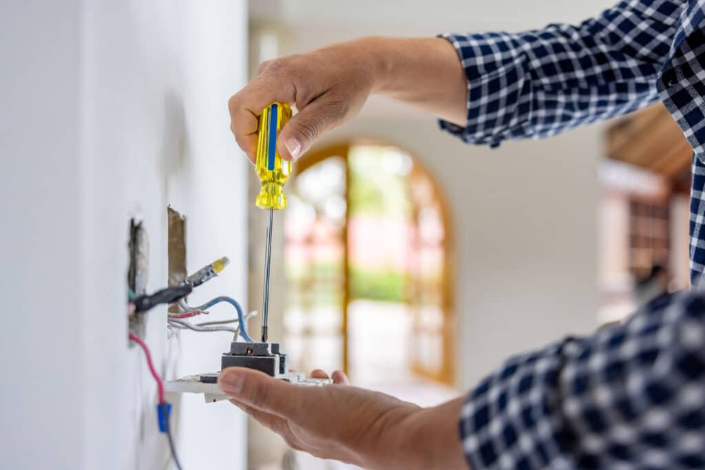 An electrician installing Electrical wiring for a power outlet.