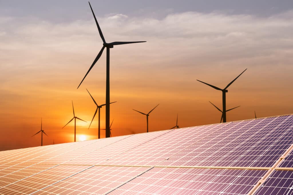 Wind turbine and solar panel at sunset—solar power and other sustainable energy sources for smart cities.